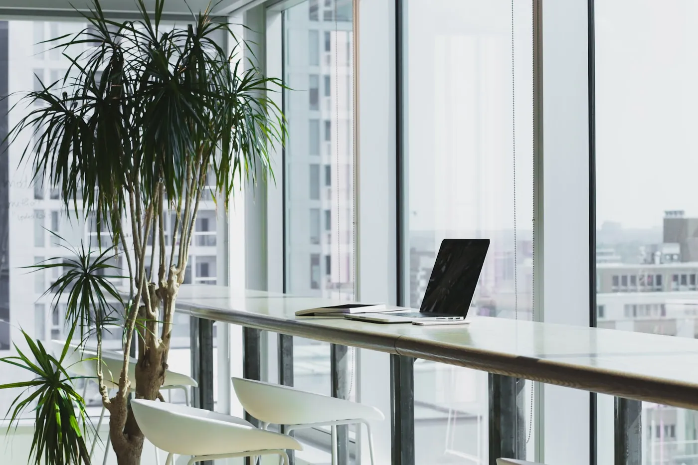 A high desk facing a glass window with a city view